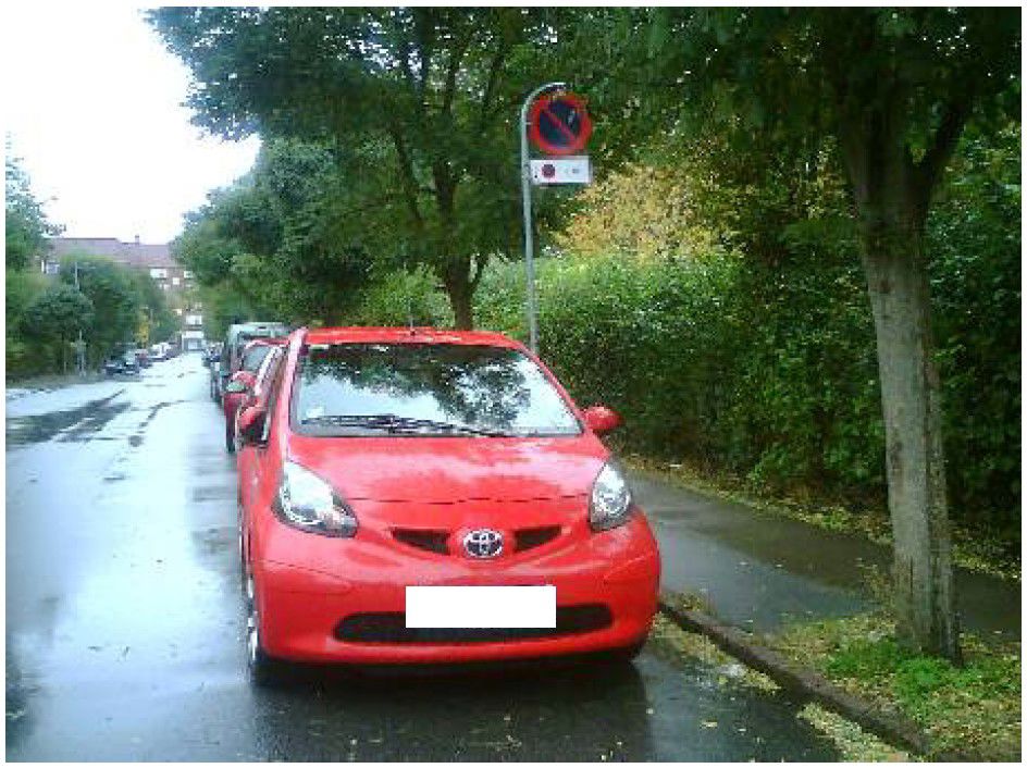 Ulovlig parkeret bil ved tavle med parkeringsforbud